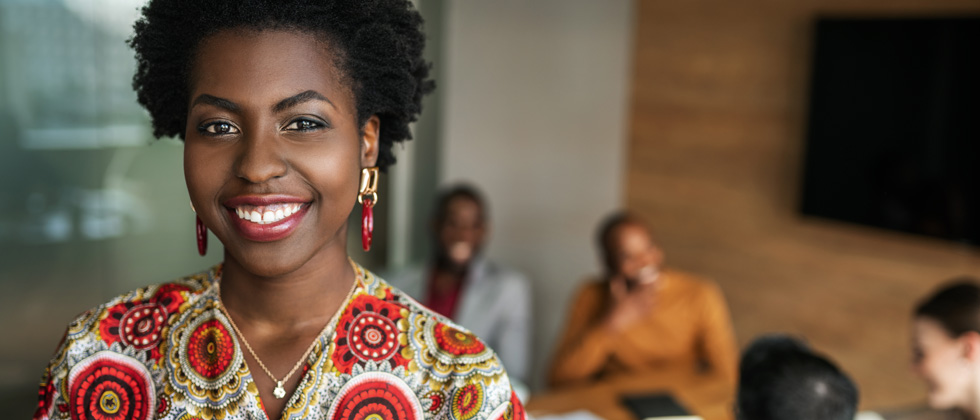 A woman smiling for the camera with a family laughing in the background