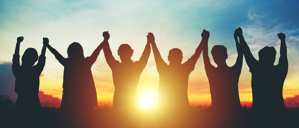 Group of friends holding hands in the sunset