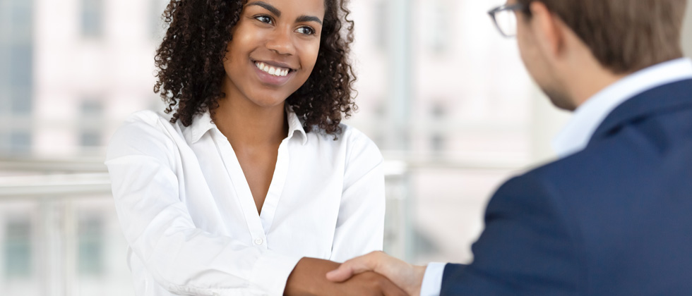 A woman in a business meeting confidently shaking someone's hand