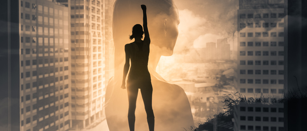 A woman with her fist up to show she is powerful while in front of a skyline