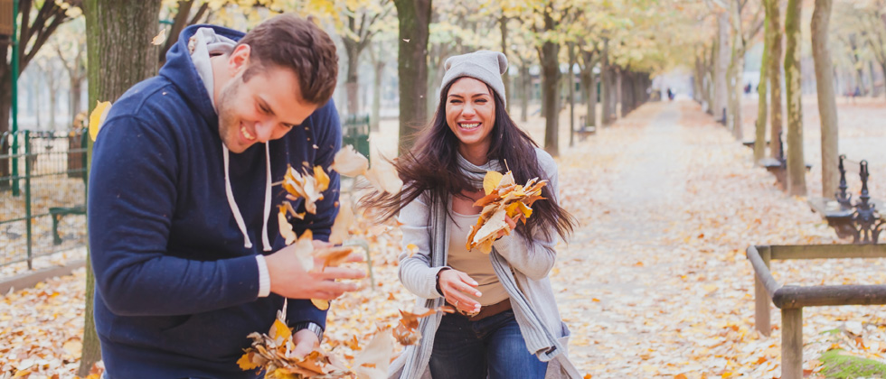 An attractive couple playing in the fall leaves together
