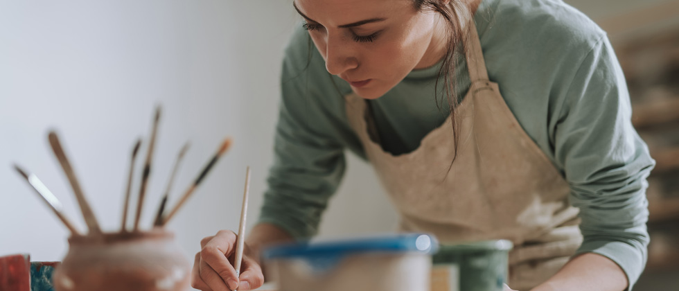 A woman in a smock working on a watercolor painting