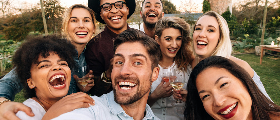 A group of friends outside laughing and drinking wine