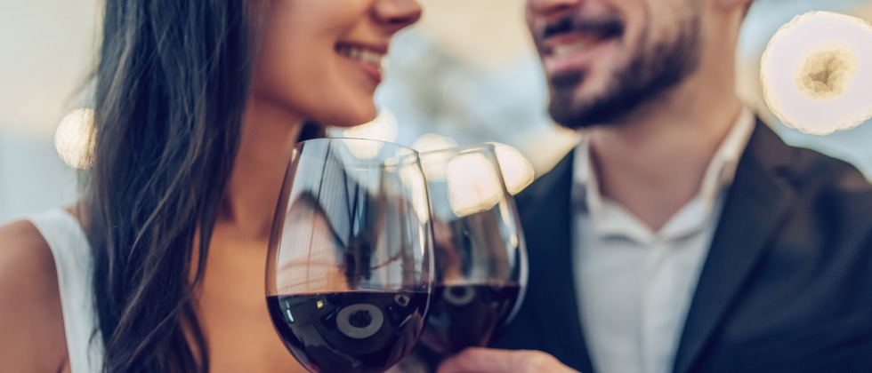 A couple on a date each enjoying a glass of red wine