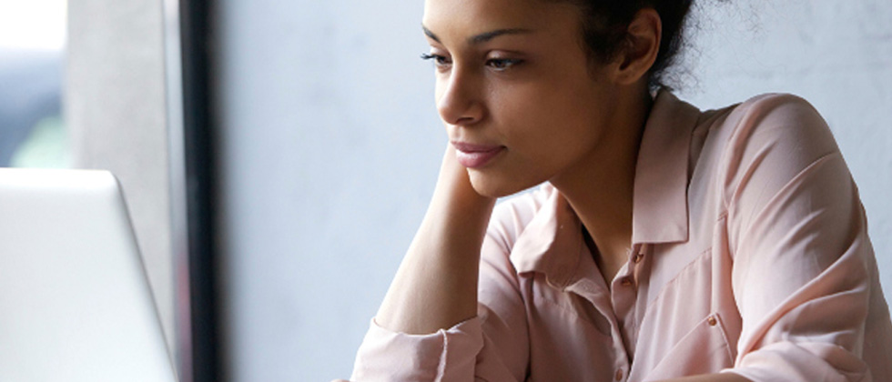A woman quietly and calmly reading something on her computer