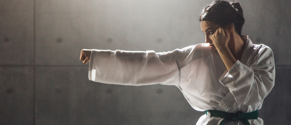 A woman in her martial arts outfit punching the air