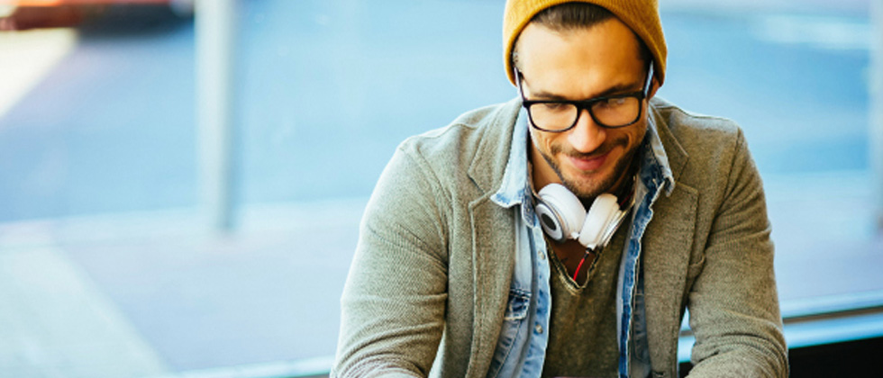A guy with headphones around his neck looking down and smiling