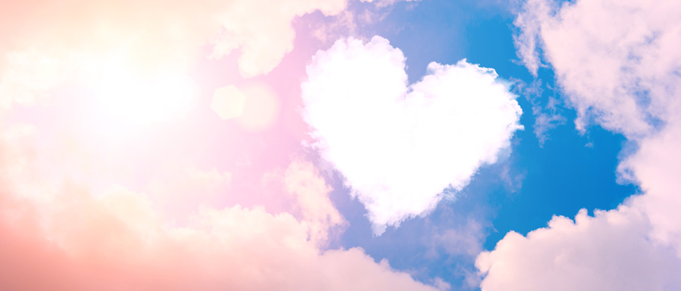 A heart shaped cloud floating in the bright blue sky