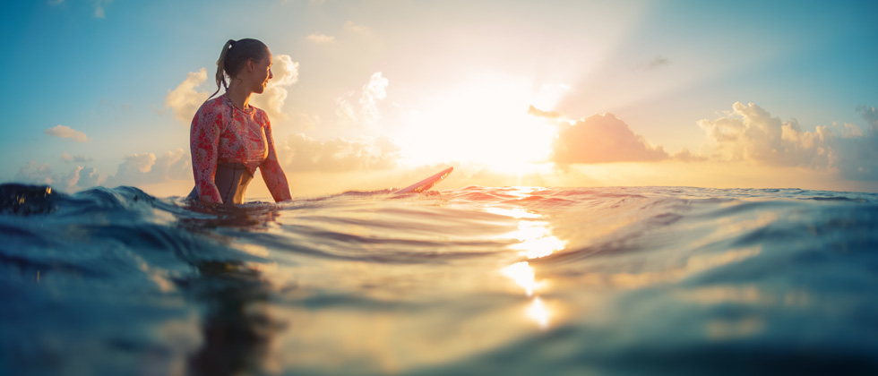 A woman surfer sitting on her board in the middle of the ocean