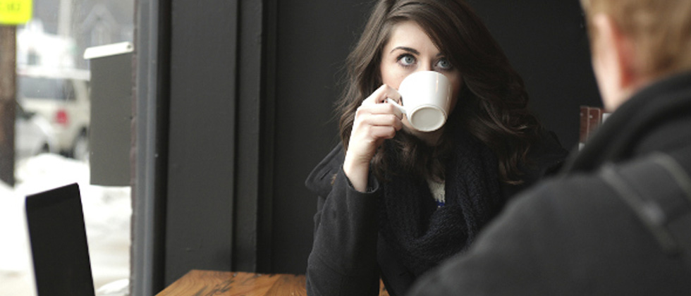 Woman drinking from a coffee mug while having an intense conversation