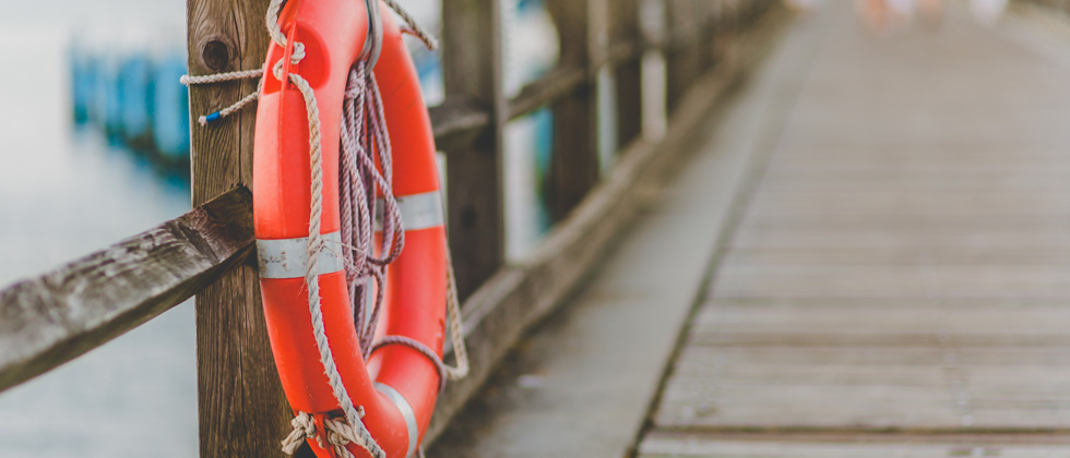 A picture of a dock with a lifesaving raft leaning against the railing