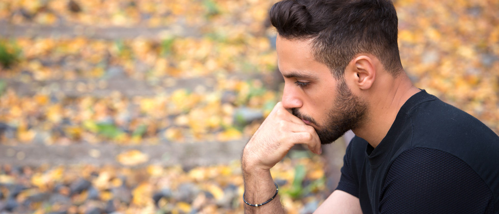 A man sitting on the side of the road looking very upset