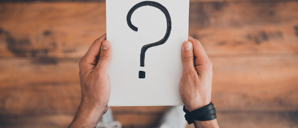 Someone holding a piece of paper with a big question mark on it