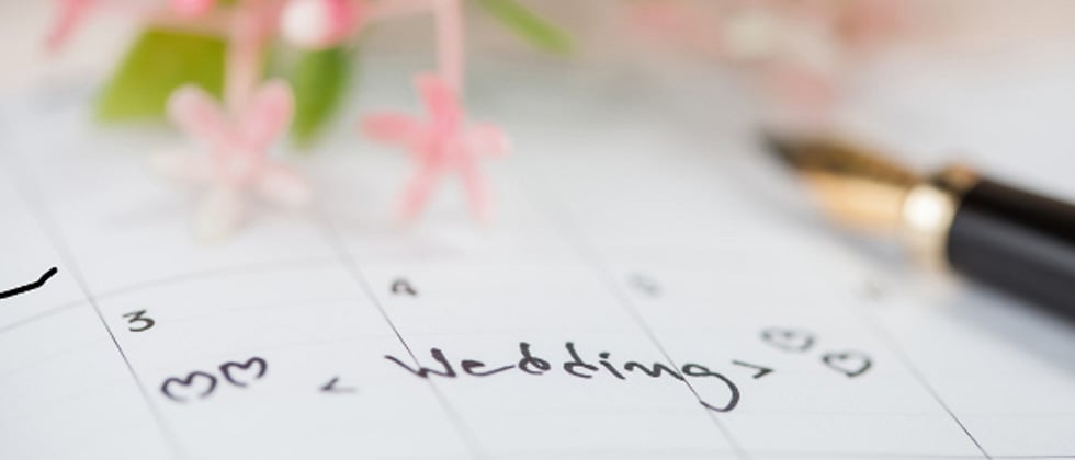 A calendar showing a date that has wedding written with hearts around it