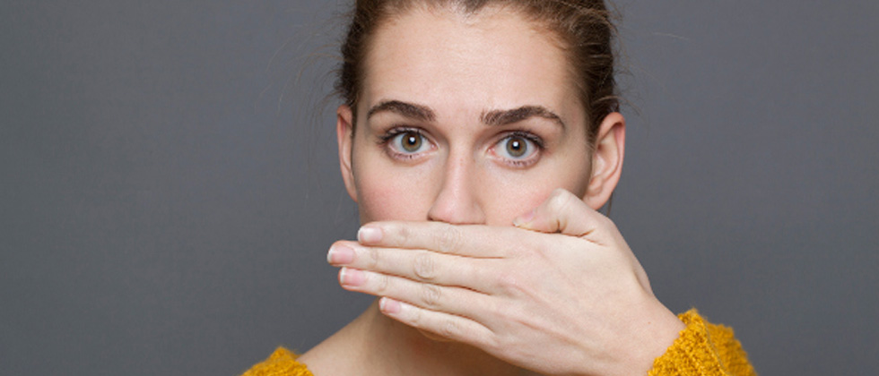 Woman staring into the camera with her hand covering her mouth