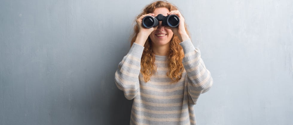 A woman looking into the camera through binoculars