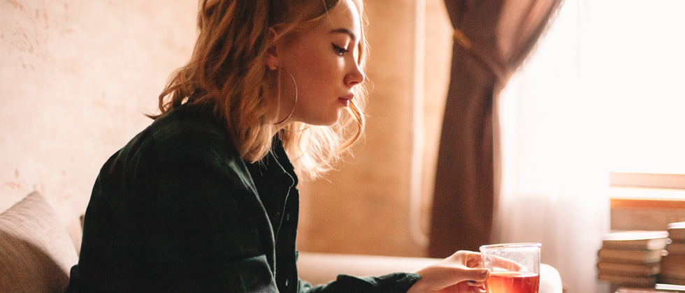 A woman sitting looking upset and holding a glass of juice
