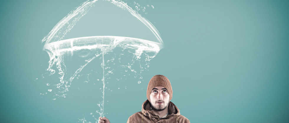 A guy standing pretending to hold the umbrella that's painted onto the wall behind him