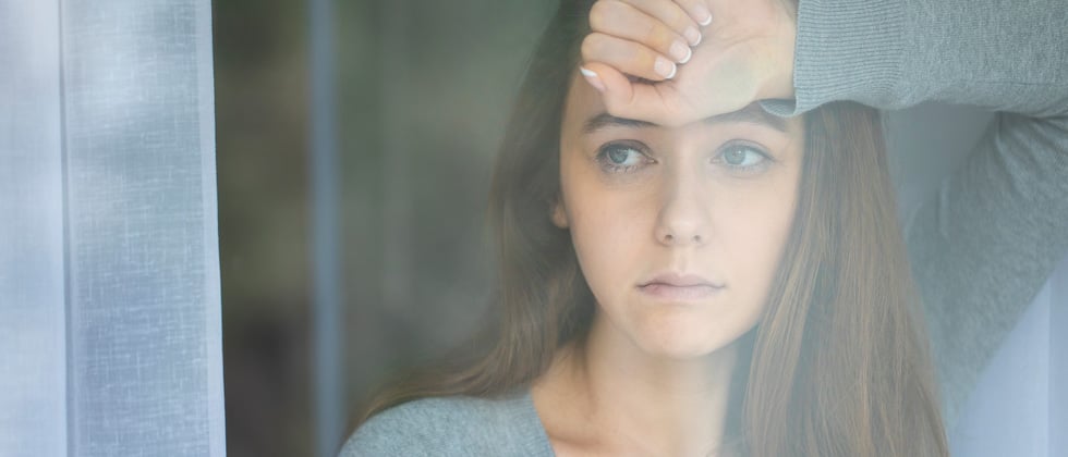 A woman looking concerned while staring out her window