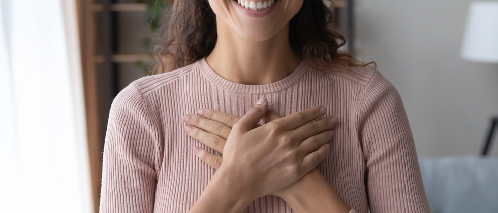 A woman standing with her hands crossing her heart
