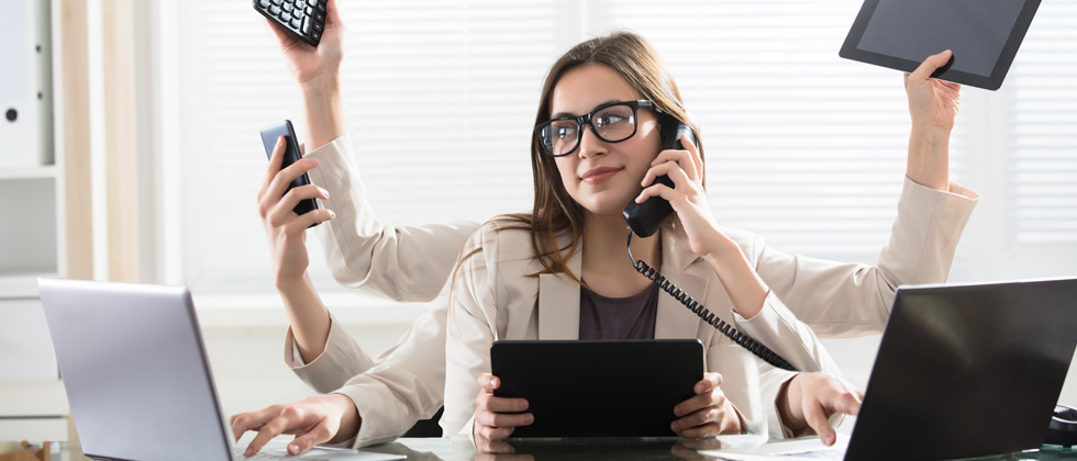 A woman sitting at a desk with 5 arms doing all different things