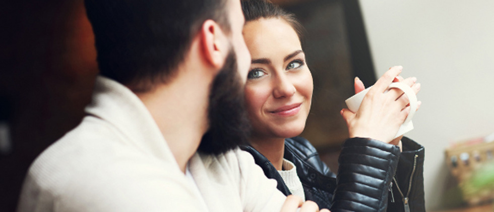 A couple smiling at each other on a date enjoying coffee