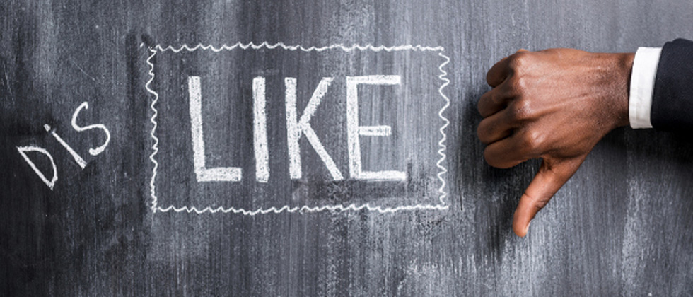 The word DISLIKE written on a chalkboard with a thumbs down sign