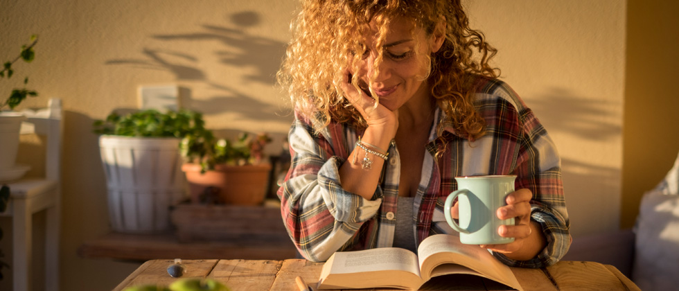 Woman sipping coffee and reading a book in the morning