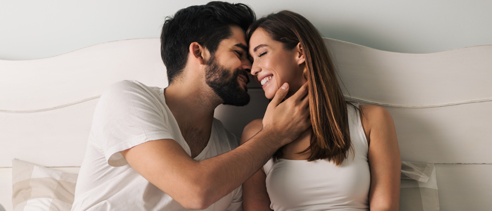 A couple sitting in bed about to kiss