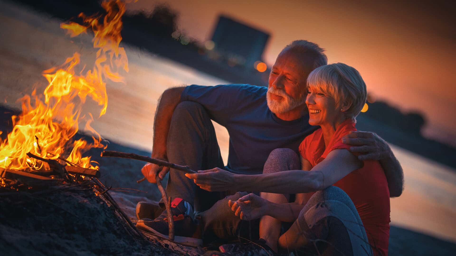 60s dating symbolized by a happy couple sitting in front of a campfire in Canada