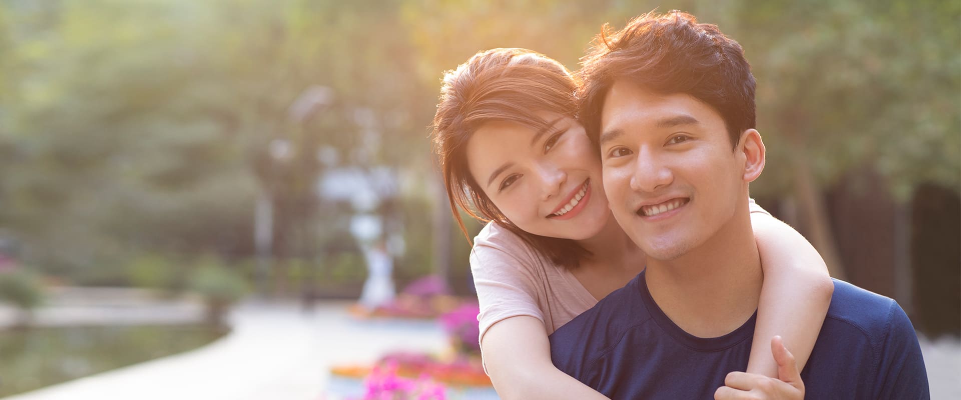Korean dating symbolized by a korean woman hugging a korean man, both smiling at the camera