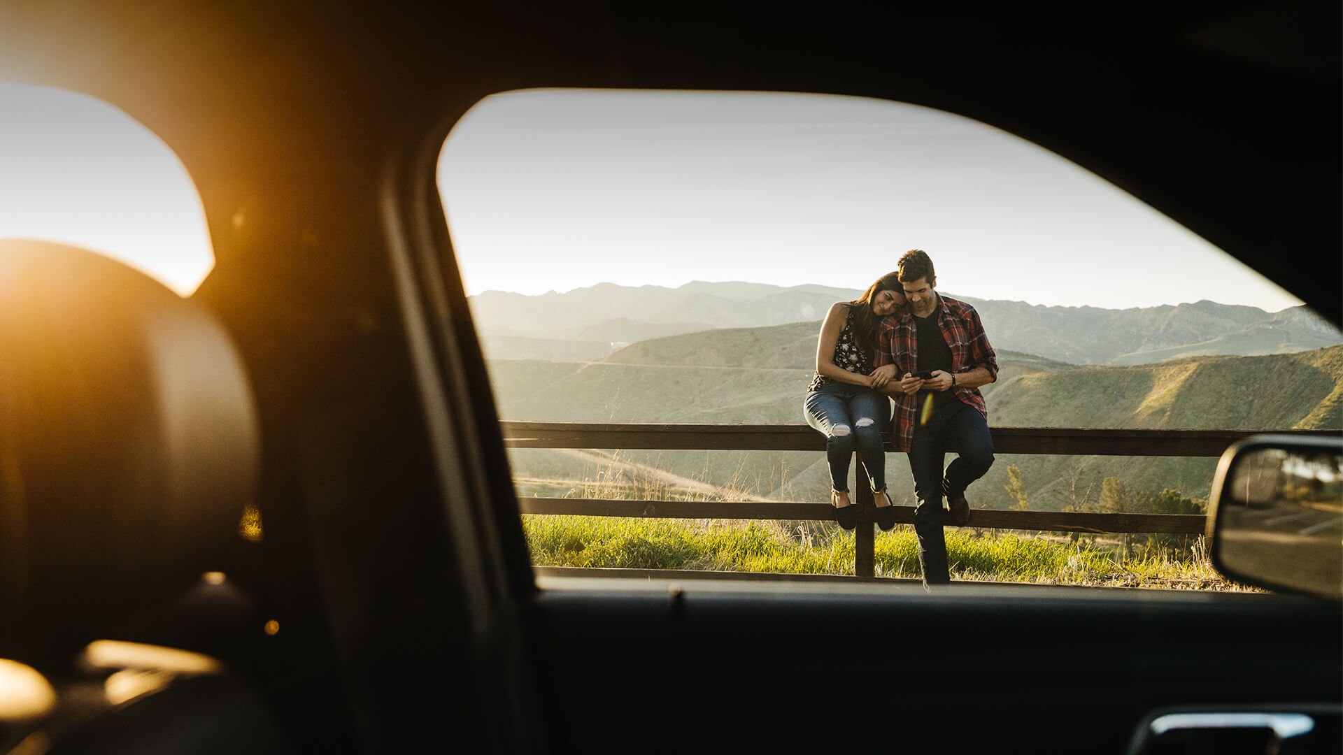 Lifestyle dating symbolized by a man and woman leaning at the fence and feeling in love with eatch other in front of a beautiful landscape