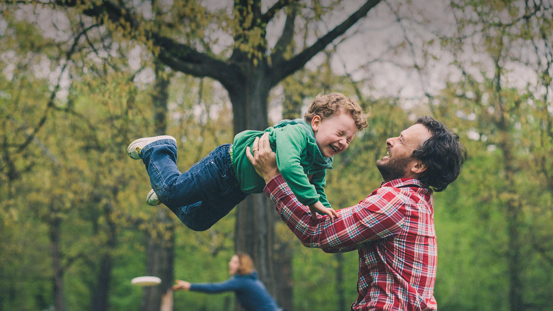 Single parent dating symbolized by a single dad who is tossing his little son in the air on a playground in canada