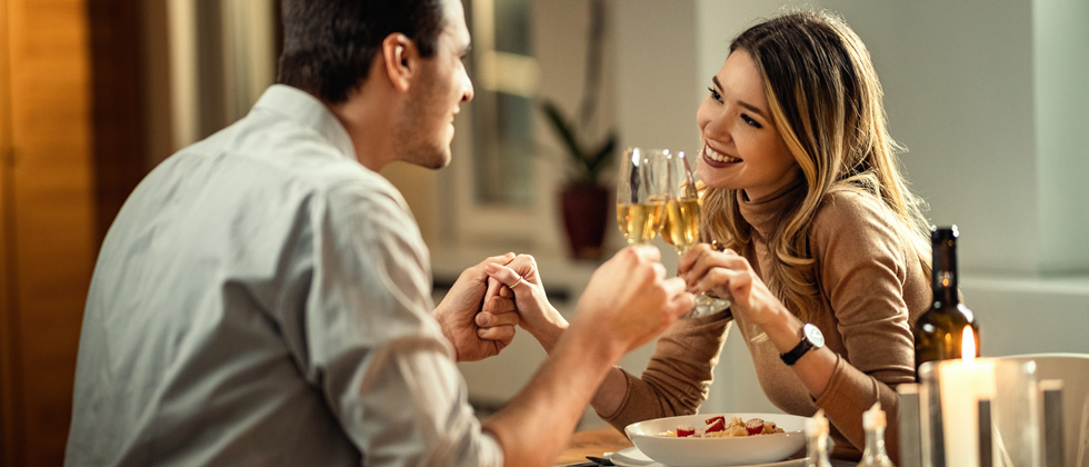 Couple on a dinner date drinking wine and holding hands