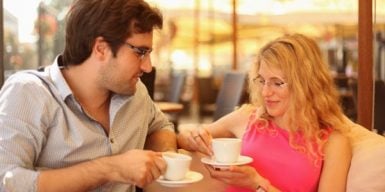 Man and woman sitting on bench looking at each other as symbol for first date tips