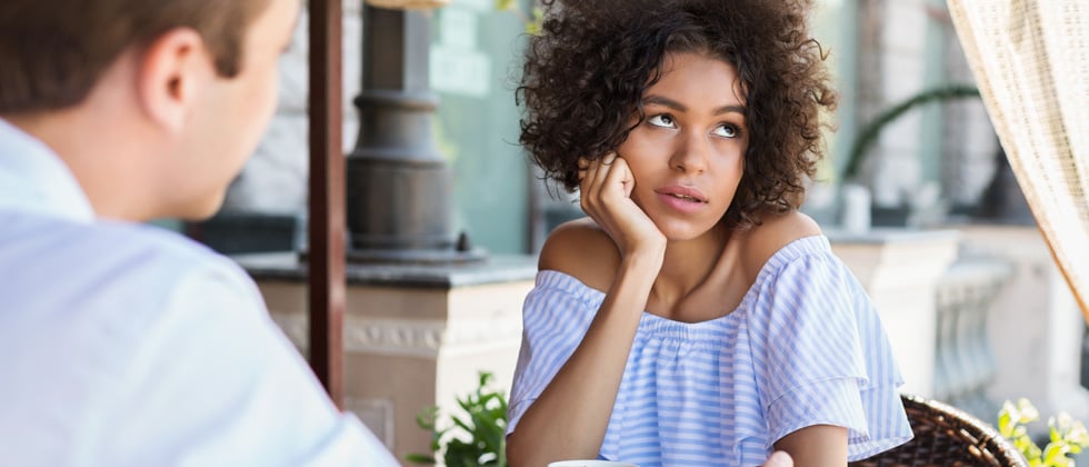 Woman at lunch with her boyfriend rolling her eyes