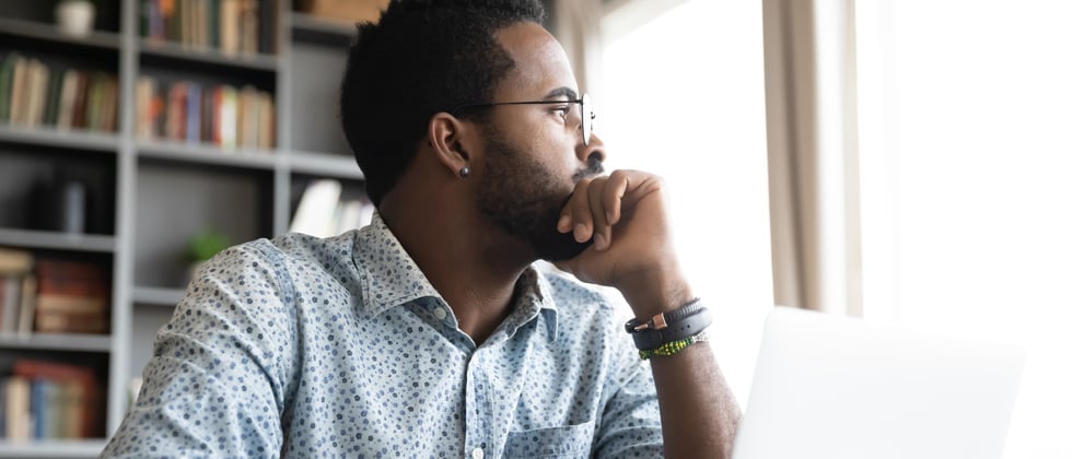 man sitting & looking into the distance deep in thought