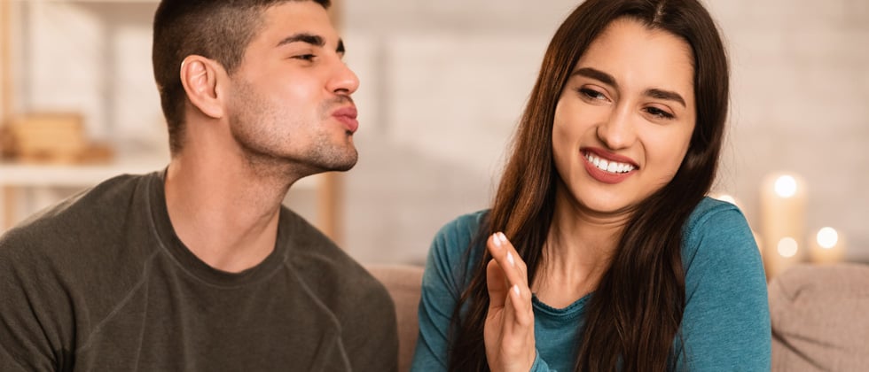 Woman holding man back from trying to kiss her