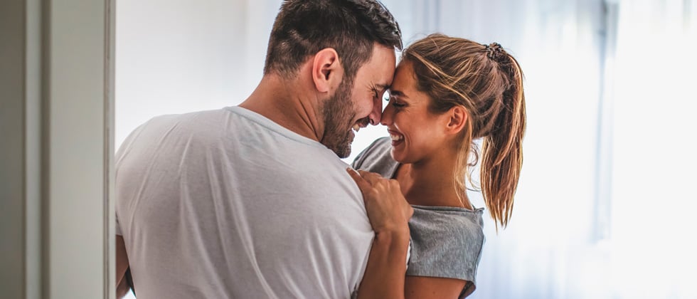 A couple holding each other, touching noses and smiling