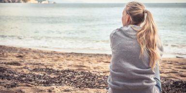 Woman looks at the sea and wonders why love hurts so much