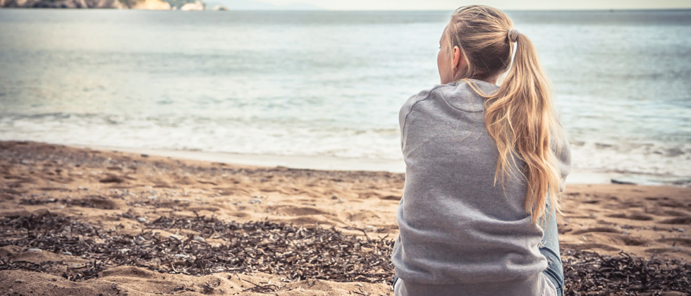 Woman looks at the sea and wonders why love hurts so much