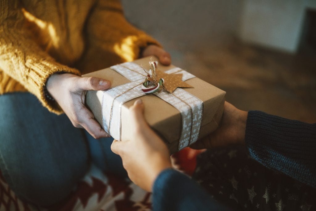 Close-up photography of two hands while giving christmas gift.