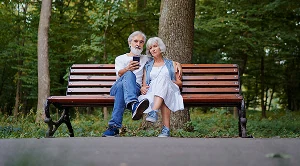 A couple relaxing on a park bench together.