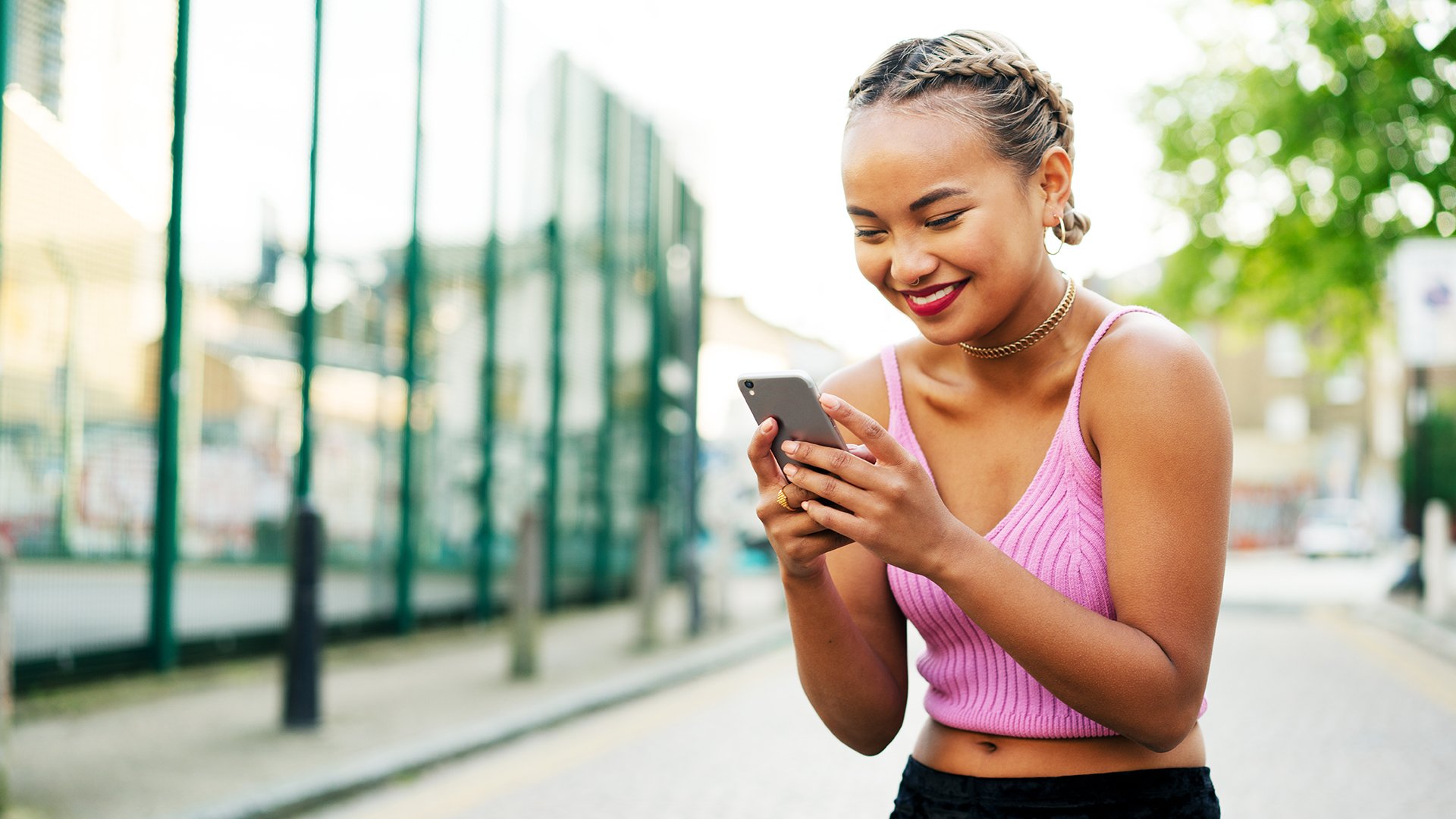 Young woman in the middle of the street laughing at her phone. Probably texting with her loved one.