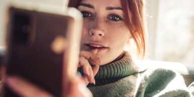 Woman looks at her cell phone and wonders to call or text