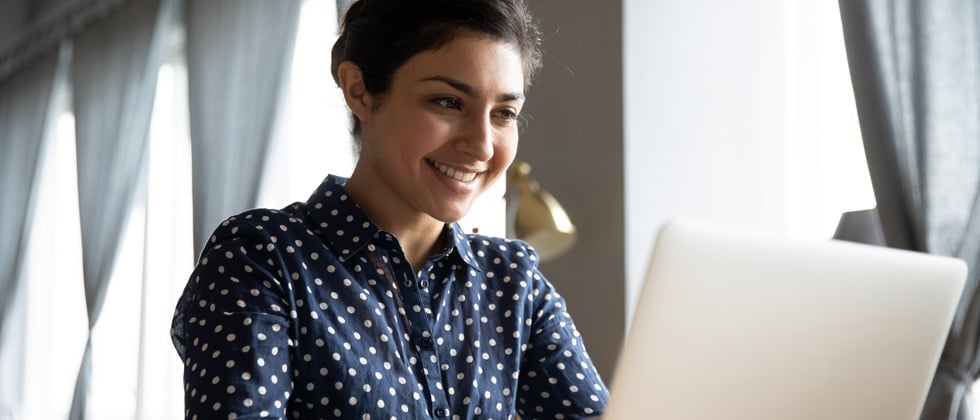 A woman smiling while looking at her laptop