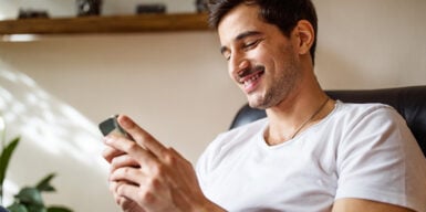 Man on mobile smiling as an example of what to text after the first date