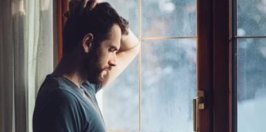 Man leans against the window and looks thoughtful as an example of when you make plans but don't write them back