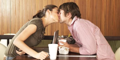 Man and woman kissing across the table as a symbol of what is dating