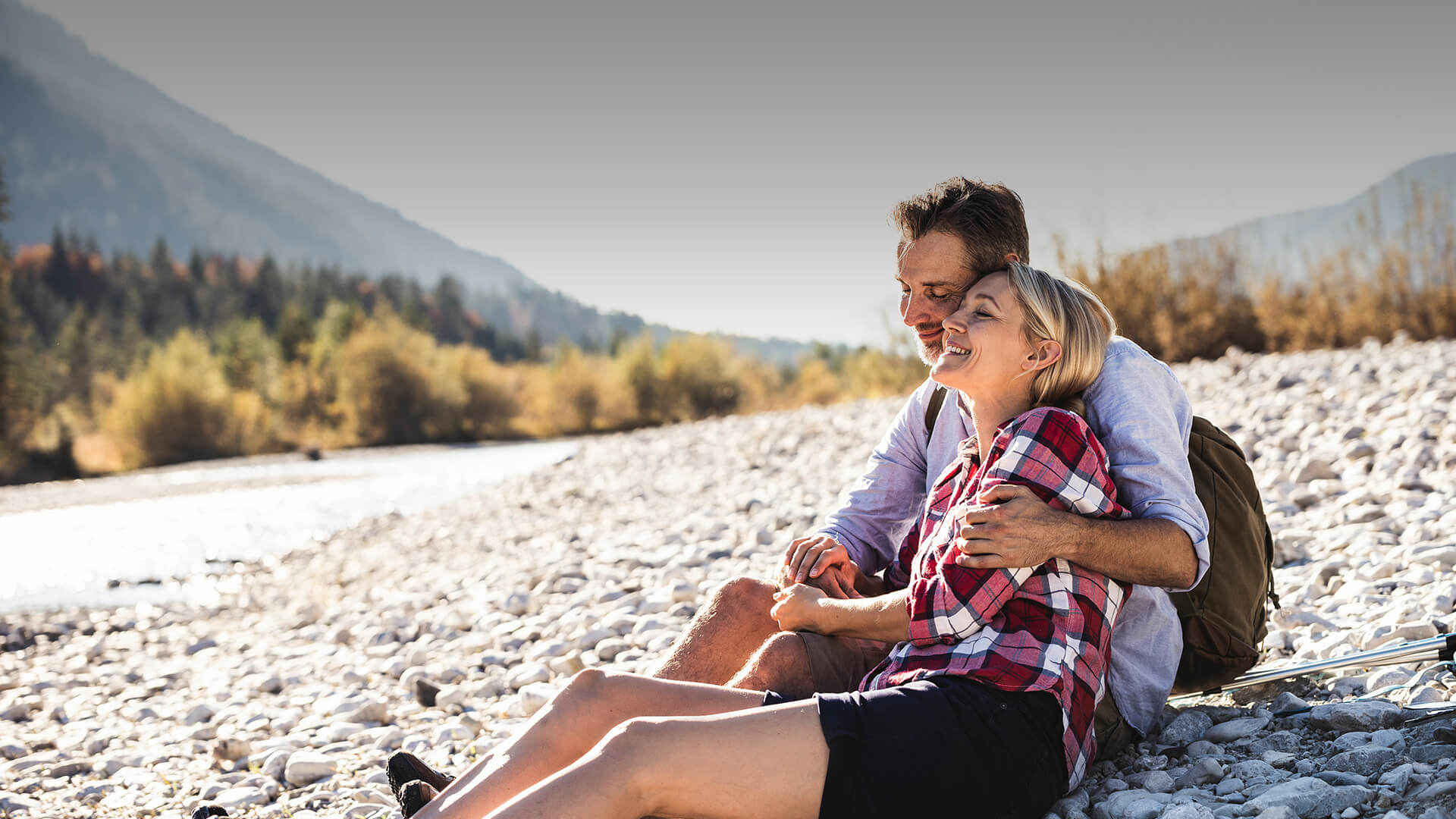 Mature Dating symbolized by a man and woman sitting at a river and enjoying the nature and their time together